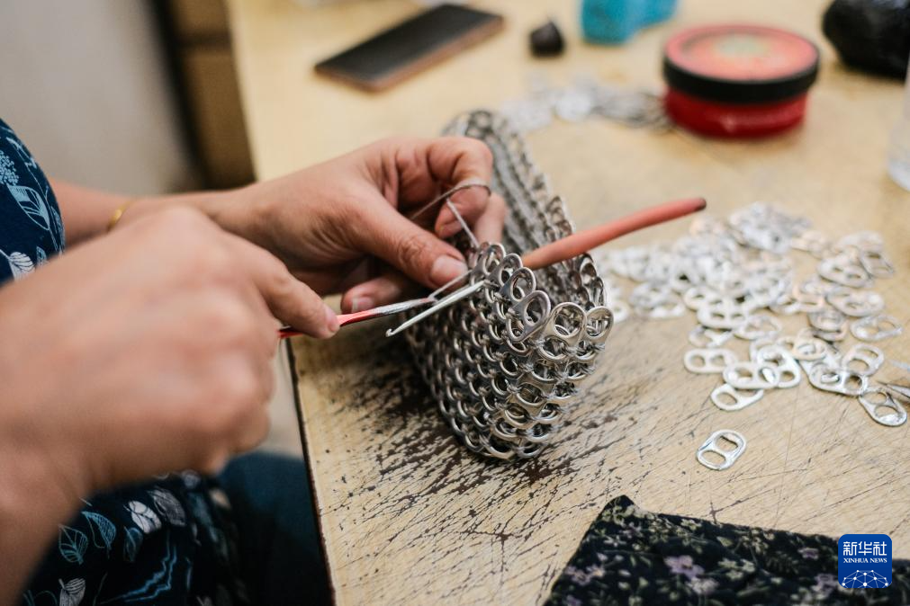 　4月21日，在位于埃及开罗“垃圾城”的手工作坊内，工作人员用易拉罐拉环制作环扣包。