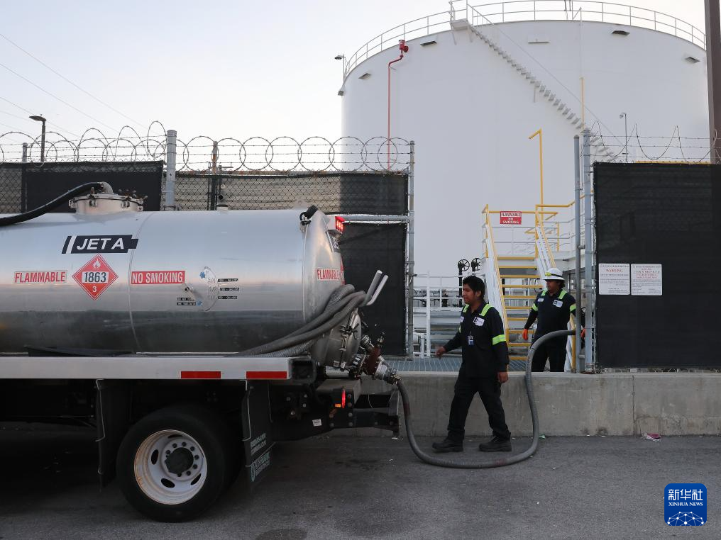 4月24日，在美国洛杉矶国际机场的航油站，工人为航空燃料油罐车注油。新华社发（邱晨摄）