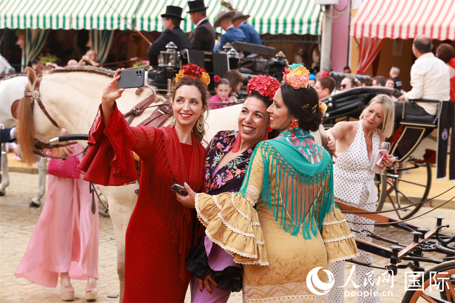 身着弗拉门戈传统服饰的女士在马车前合影留念。 人民网记者 许海林摄