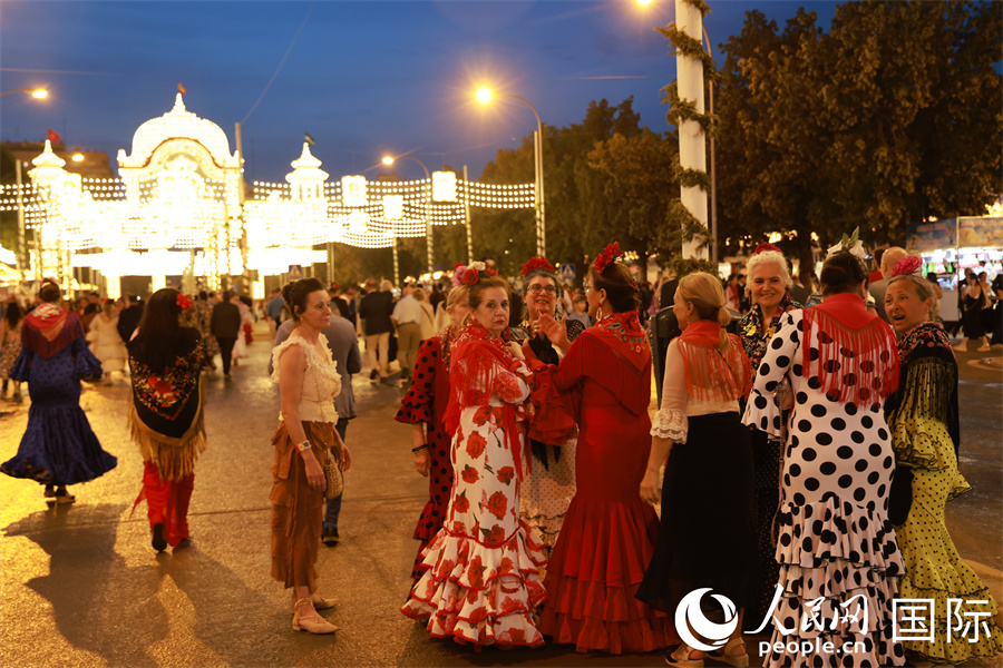 数位当地民众结伴参加四月节庆典，在主入口门楼前大街讨论如何合影留念。 人民网记者 许海林摄