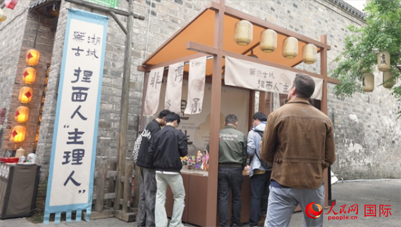 芜湖古城游客在捏面主理人摊位前驻足。人民网记者 苏缨翔摄