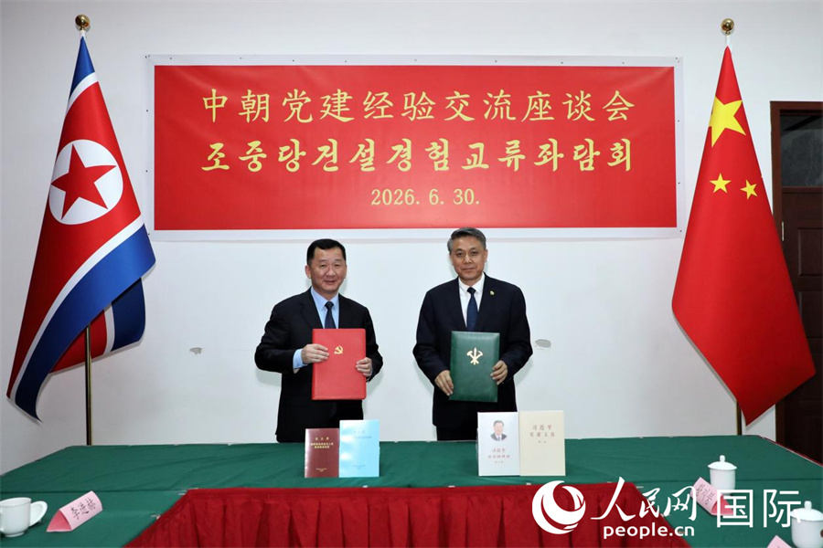 6月30日，中朝党建经验交流座谈会在平壤举行。图为王亚军和文成革互赠中朝两党党建图书。 人民网记者 刘融摄