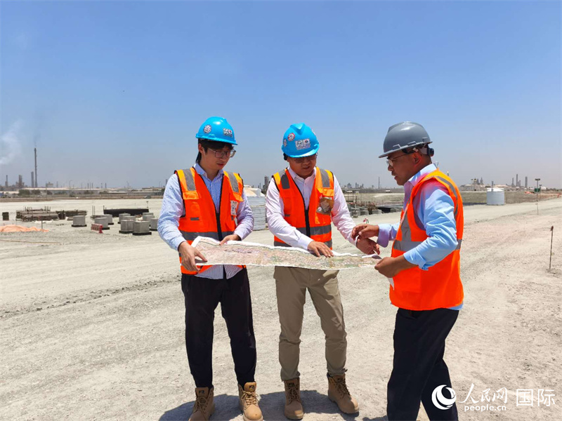 在中午49℃的施工现场,中方技术人员正在研究图纸优化施工方案。 人民网记者 黄培昭摄