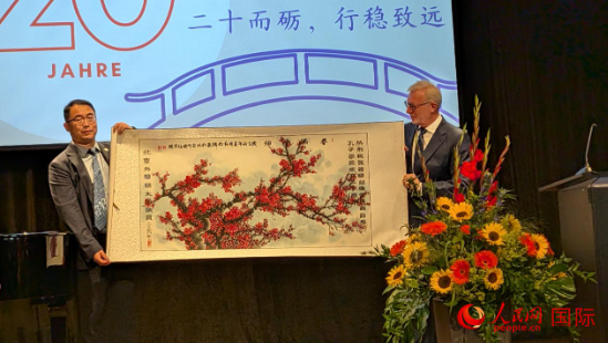 图为丁浩向孔院赠送“春满乾坤”画卷。刘仲华摄