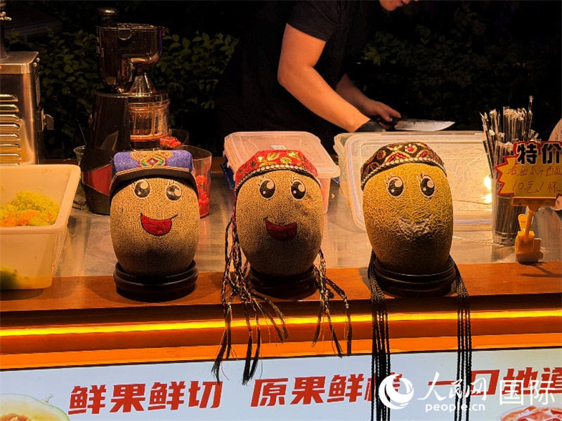 阿勒屯古街上,一位摊主给自己的哈密瓜画上表情。人民网 柯明可摄