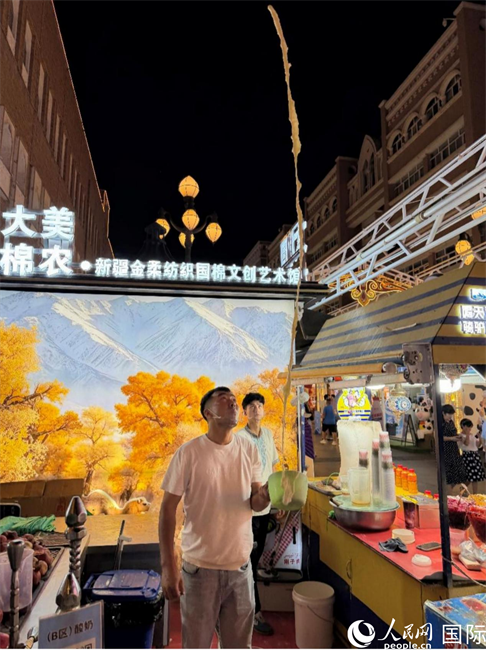 新疆国际大巴扎内，一名摊主将酸奶刨冰高高抛起。人民网 柯明可摄