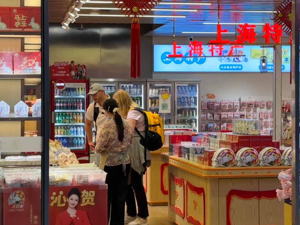 国庆假期，外国游客在上海虹桥火车站内购买上海特产。新华社发（陈晨 摄）