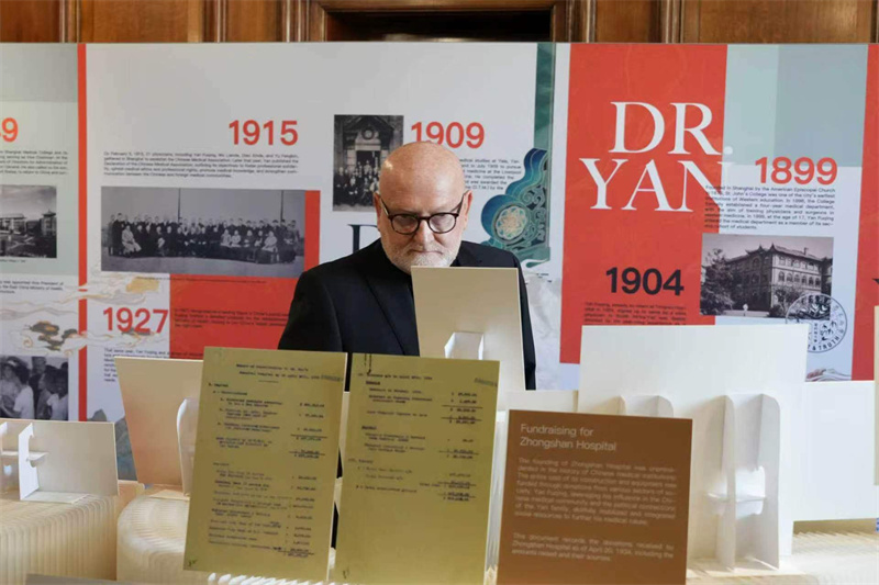 “先驱者颜福庆”海外巡展英国站展览现场，一位参观者在仔细观看展品。主办方供图