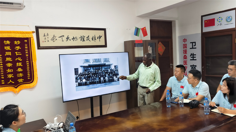 哈吉老院长和医疗队一起回顾老照片。中国援桑医疗队供图