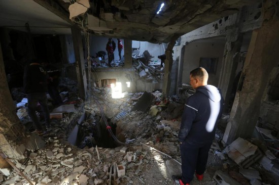 12月16日,在加沙地带中部努赛赖特难民营,人们查看以军袭击后的建筑废墟。新华社发(里泽克·阿卜杜勒贾瓦德摄)