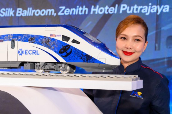 12月18日,在马来西亚普特拉贾亚,模特与新的动车组模型合影。新华社发(张纹综摄)