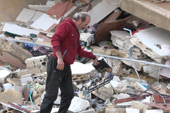 2月21日,在黎巴嫩南部的迈斯杰贝勒,一名返回家园的男子查看废墟中的物品。新华社发(塔希尔·阿布·哈姆丹摄)