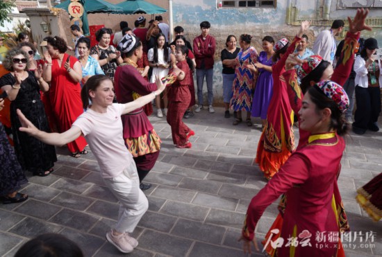 5月24日,在库车市龟兹小巷,俄罗斯塔斯社高级记者安娜·福米娜和演员们共舞。