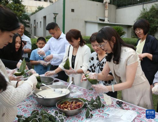 5月27日，在伊朗首都德黑兰，人们在中国驻伊朗大使馆举行的“香囊飘香 端午安康”节日庆祝活动上体验包粽子。新华社记者 沙达提 摄