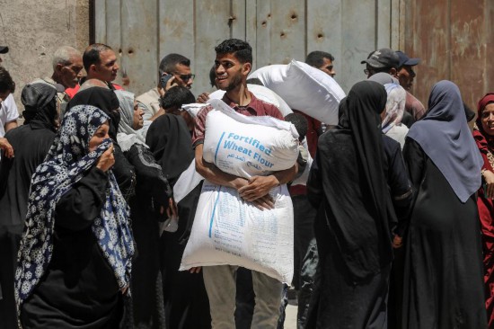 6月26日，巴勒斯坦人在加沙城领取援助物资。新华社发（里泽克·阿卜杜勒贾瓦德摄）