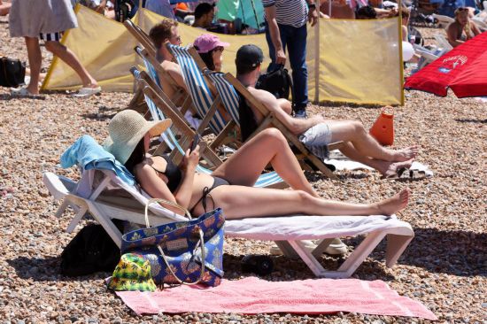 2025年7月12日,人们在英国南部布赖顿的海滩休闲。英国气象局11日发布公告说,英格兰大部分地区都已达到热浪标准,高温健康警报已升级为琥珀色。这是英国今年夏季遭遇的第三波热浪。新华社发