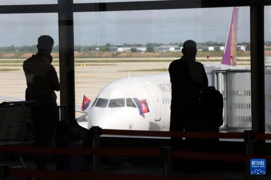 9月9日,在柬埔寨干丹省,乘客在德崇国际机场的候机楼内观看客机停靠。新华社发(索万纳拉摄)