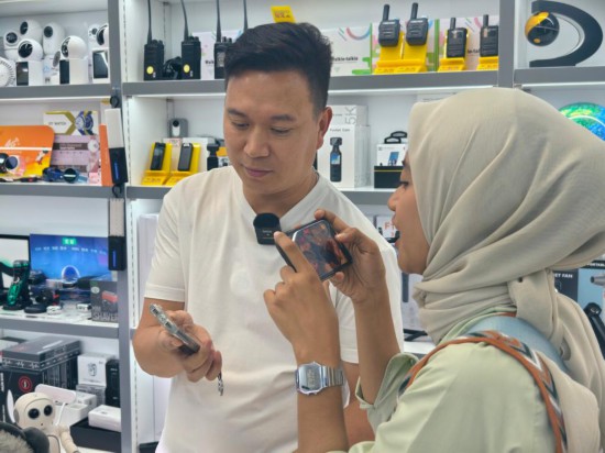 9月26日,在浙江金华义乌国际商贸城,印度尼西亚拉贾瓦里电视台的新闻记者奥利维娅·费拉里(右)使用AI翻译机与中国老板李军交流。新华社记者 刘梓漪 摄