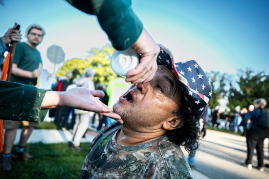 9月26日,在位于美国芝加哥西郊布罗德维尤市的移民与海关执法局办事机构外,执法人员发射的催泪弹伤及一名抗议者,同伴在为他进行紧急处置。新华社发(文森特·约翰逊摄)