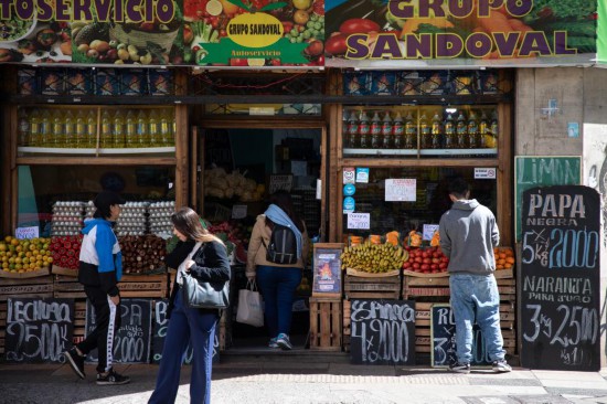 9月25日,在阿根廷首都布宜诺斯艾利斯,人们走过一家张贴着特价广告的蔬果店。新华社发(马丁·萨巴拉摄)