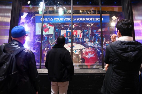 2024年11月5日,人们在美国纽约时报广场观看实时出口民调。新华社记者李睿摄