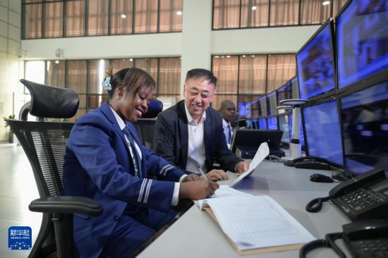 9月30日,在蒙内铁路内罗毕终点站调度中心,女调度员达玛丽斯·穆廷达与负责蒙内铁路运营的非洲之星铁路运营公司运输部负责人冯旭东一起查阅工作日志。新华社记者 杨光 摄