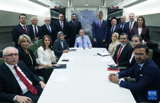 10月14日,土耳其总统埃尔多安(中)在出席沙姆沙伊赫峰会后返回土耳其的专机上与随行记者合影。新华社发(土耳其总统府供图)