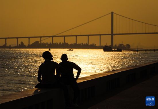 9月11日,在莫桑比克首都马普托,两名莫桑比克人在马普托大桥前的海边休息。新华社记者 韩旭 摄