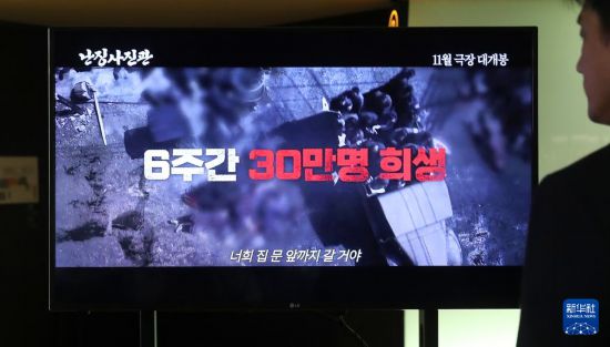 11月5日,韩国观众在首尔一家电影院宣传屏幕前观看《南京照相馆》预告片。新华社记者 姚琪琳 摄