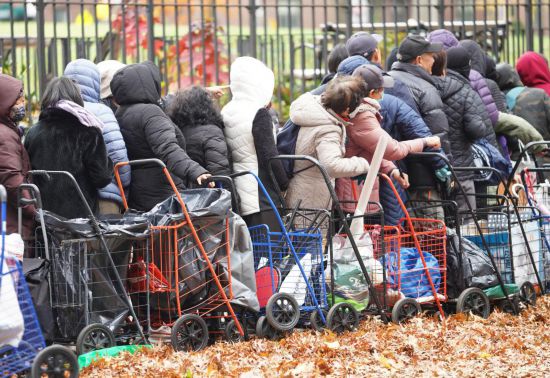 11月12日,人们在美国纽约一处食物发放点领取食物。新华社记者张凤国摄