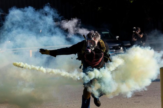 9月26日,在位于美国芝加哥西郊布罗德维尤市的移民与海关执法局办事机构外,抗议者在冲突中将执法人员发射的催泪弹瓶扔回。新华社发(文森特·约翰逊摄)