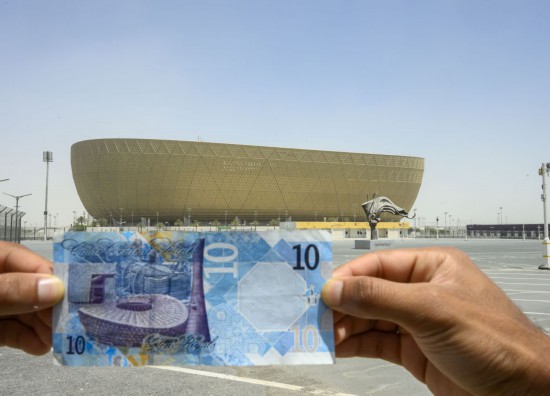 这是2025年4月17日在卡塔尔首都多哈以卢赛尔体育场为背景拍摄的卡塔尔10里亚尔纸币,纸币左边图案为卢赛尔体育场。