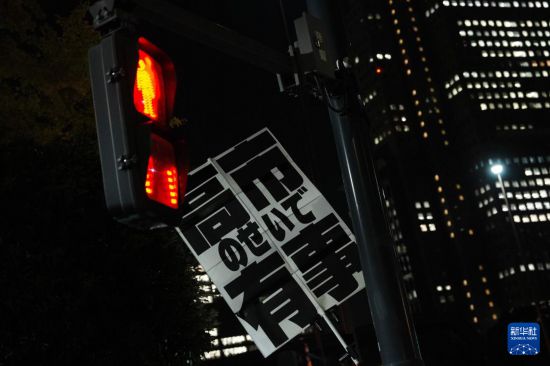 11月21日,在日本东京的首相官邸外,民众举起标语参加抗议活动。新华社记者 贾浩成 摄