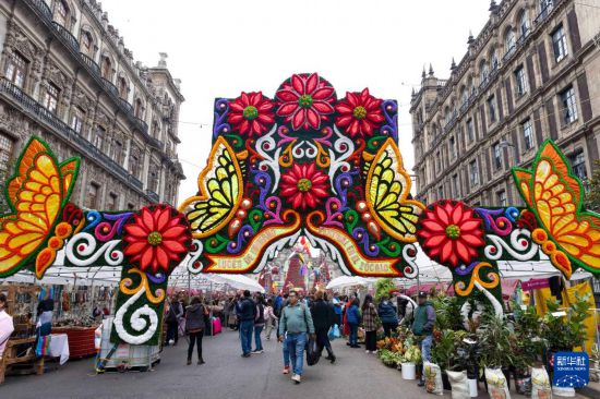 12月30日，在墨西哥首都墨西哥城，人们走过宪法广场附近的节日装饰。新华社记者 李梦馨 摄