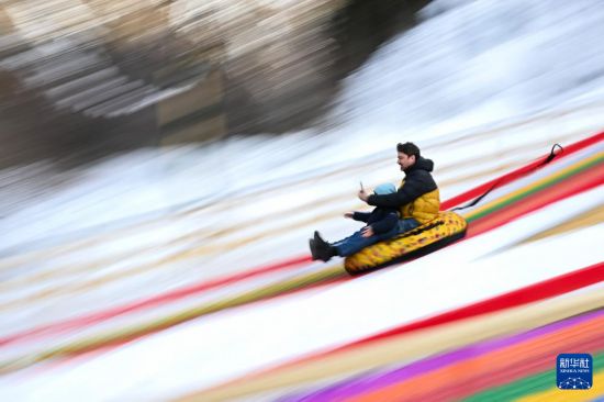 1月11日，在哈萨克斯坦阿拉木图市郊，一名男子带着孩子体验冰雪滑梯。新华社记者 李任滋 摄