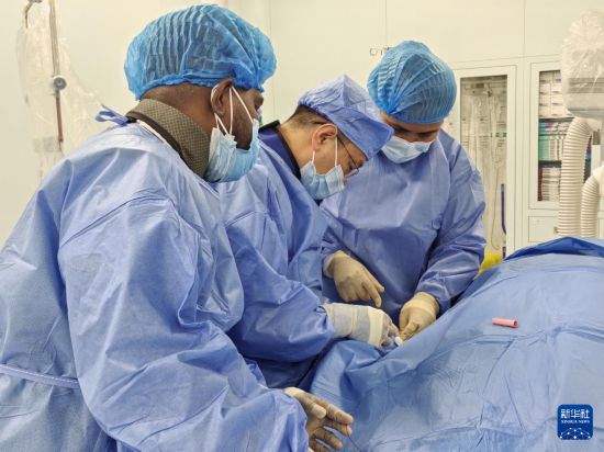 2025年6月5日,在所罗门群岛首都霍尼亚拉国家转诊医院综合医疗中心内,中国医疗队队员(中)与当地医生为一名当地患者实施所罗门群岛首例急性下壁心肌梗死介入治疗。新华社发(第四批援所罗门群岛中国医疗队供图)