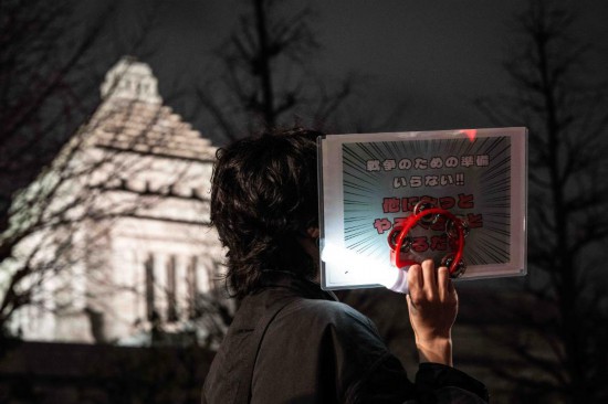 2月24日,在日本东京的众议院第二议员会馆前,民众手持标语参加抗议活动。新华社记者贾浩成摄