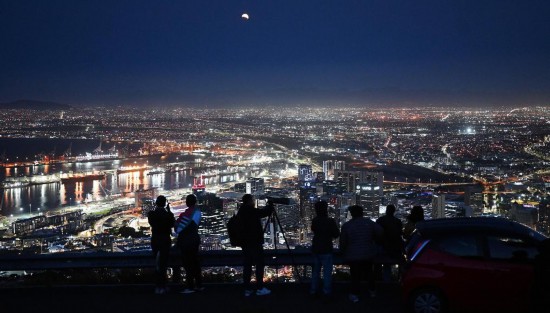 2025年9月7日，在南非开普敦，人们观看城市夜空中的月食。新华社发（哈比索·姆卡贝拉摄）