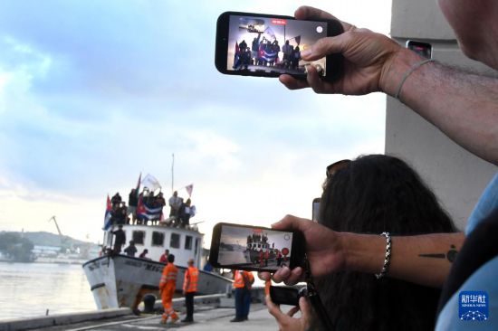 3月24日，在古巴首都哈瓦那，民众用手机拍摄“格拉玛2.0”号抵达的画面。新华社发（华金·埃尔南德斯摄）