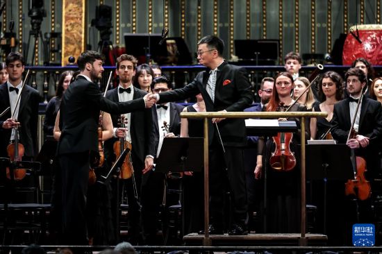 3月25日，在匈牙利布达佩斯，中国音乐学院院长李心草（前右）与匈牙利小提琴手握手。新华社发（鲍洛格·达维德摄）