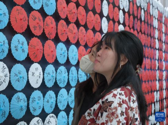 4月25日，在印度尼西亚普禾加多，两个女孩在普华三语学校观看装饰墙上的中文字。新华社记者 李富玉 摄