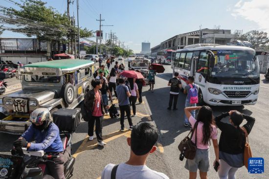 3月19日，在菲律宾奎松市，人们等候乘坐“吉普尼”公交车。新华社发（乌马利摄）