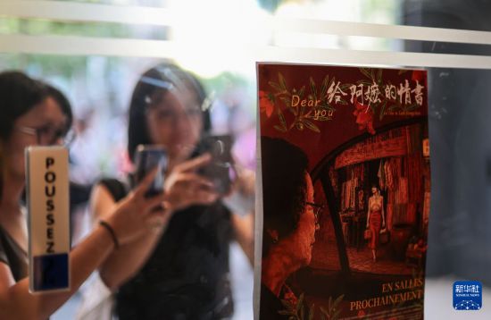 7月5日，在法国巴黎，人们拍摄中国电影《给阿嬷的情书》的海报。新华社记者 邬惠我 摄