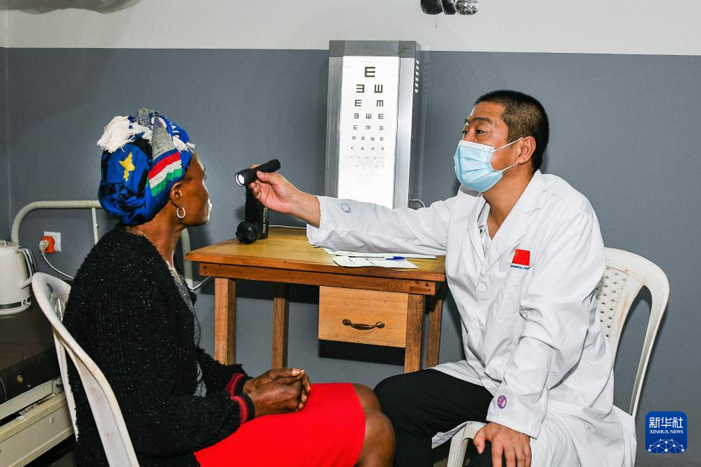 7月24日,在喀麦隆首都雅温得郊外的阿法诺亚村,中国援喀麦隆医疗队队员为当地患者检查眼睛。新华社发(科普索摄)