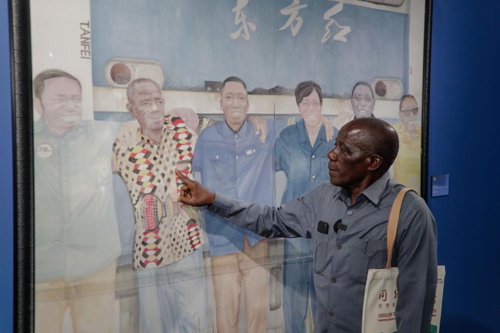 11月26日,在坦桑尼亚达累斯萨拉姆,坦赞铁路退休职工索罗蒙·姆瓦卡桑加在“同路朋友——坦赞铁路采风绘画展”上认出画中的自己。新华社发(赫尔曼·埃马纽埃尔摄)